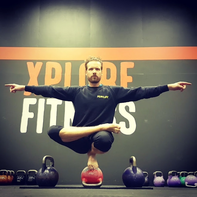 Chris balancing on a kettlebell in the gym